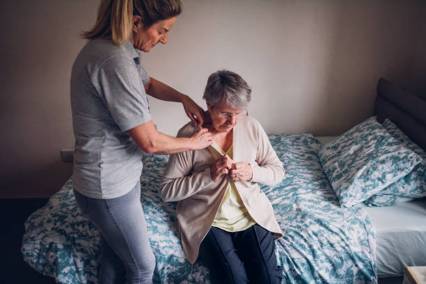 Home Help for Senior Woman at Home The woman is helping a senior woman dress in her bedroom. getting dressed stock pictures, royalty-free photos & images