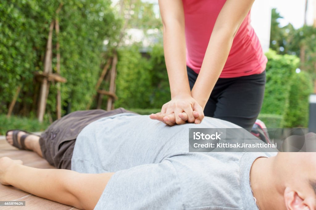 Woman giving cardiopulmonary resuscitation (CPR) to a man at public park. Woman giving cardiopulmonary resuscitation (CPR) to a man at public park CPR Stock Photo