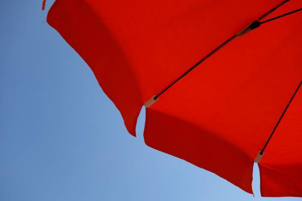 istock orange beach umbrella in the wind 665832210