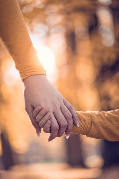 madre e figlio che si tengono per mano nel parco pubblico - holding hands human hand child mother foto e immagini stock