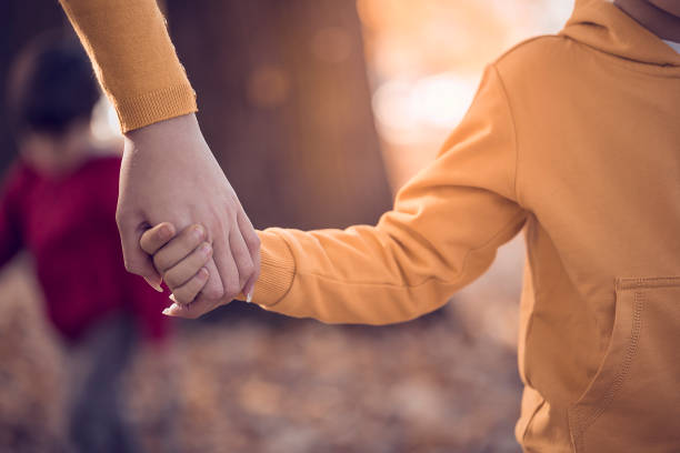 istock Mother and child holding hands in public park 665856140