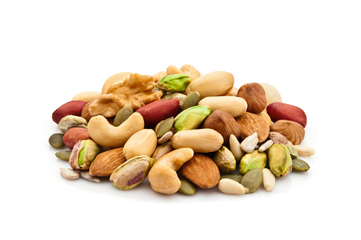 Macro shot of mixed nuts arranged in a heap isolated on white background. Nuts included in the composition are pistachios, hazelnut, pine nut, almonds, pumpkin seeds, macadamia nuts, sunflower seeds, peanuts, cashew and walnuts. DSRL studio photo taken with Canon EOS 5D Mk II and Canon EF 100mm f/2.8L Macro IS USM