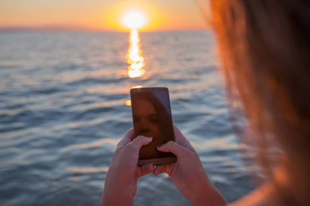 istock Cute girl with mobile phone on beautiful sunset background 665878696