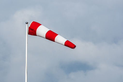 Red and white windsock on pole.