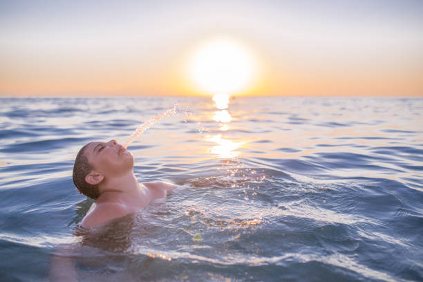 istock boy playing with water on the beach in summer. 665886286