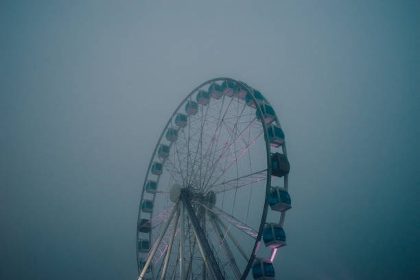 Ferris wheel in the park at dawn. Wonderful summer landscape. The sun's rays illuminate the morning mist.