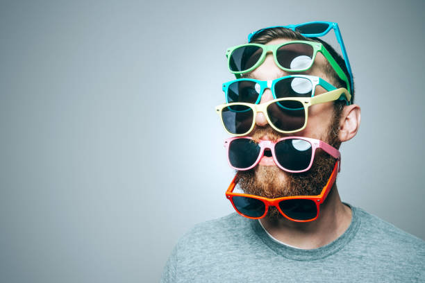 Colorful Sunglasses Portrait A portrait of a man with a large beard, wearing multiple pairs of multi-colored sunglasses.  Studio shot; horizontal with copy space. sunglasses photos stock pictures, royalty-free photos & images
