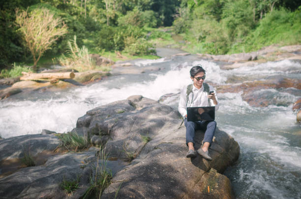 istock Businessman with backpack and laptop and phone at  waterfall  the forest. 665894106