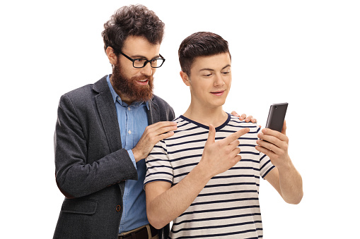 Teenage son showing something on a phone to his father isolated on white background