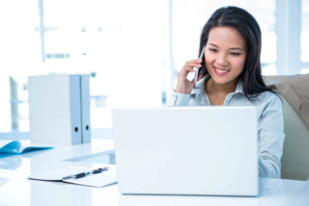 istock Smiling businesswoman on phone using laptop 665906454