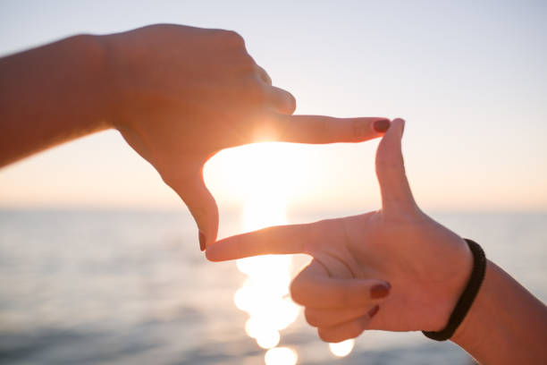 istock finger frame- woman's hands capture the sunset on backlit on background. 665907096