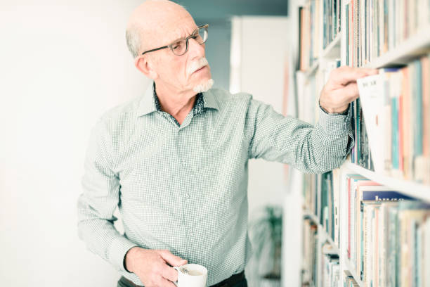 istock Senior man looking for book in bookcase. 665907150