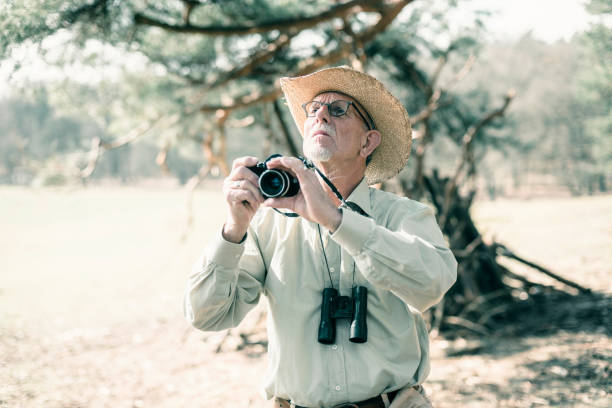 istock Senior man with hat photographing nature. 665907184