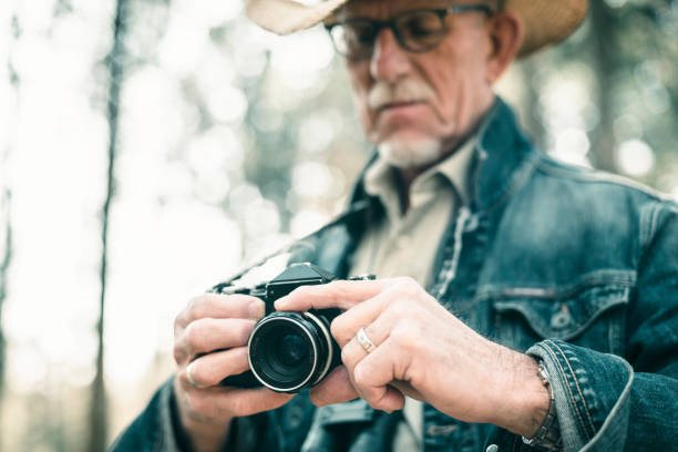 istock Senior photographer in forest adjusting camera. 665907300