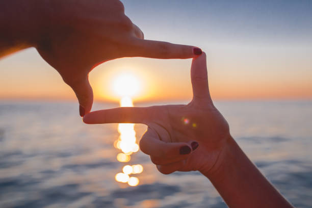 istock finger frame- woman's hands capture the sunset on backlit on background. 665907562