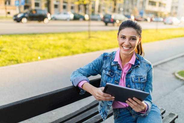 istock Cheerful woman sitting on bench and using digital tablet 665910306
