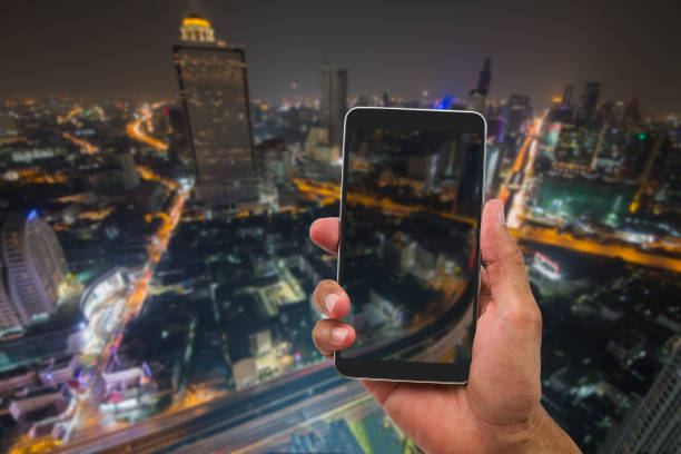 istock Hand holding mobile phone on blurred city light 665910564