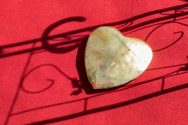 big golden heart on a red carpet with shadow