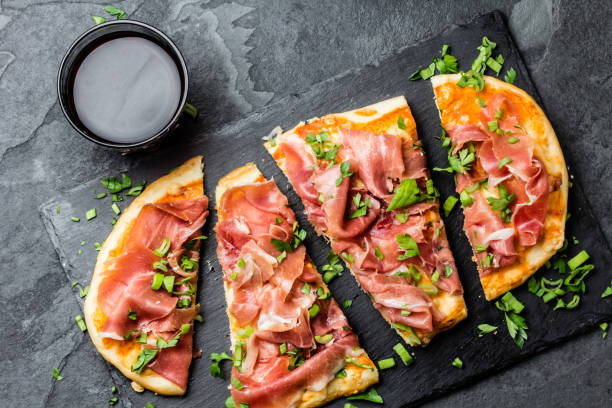 homemade pizza with jamon serrano served on slate plate with glass of red wine - serrano chilli pepper meat ham spain imagens e fotografias de stock