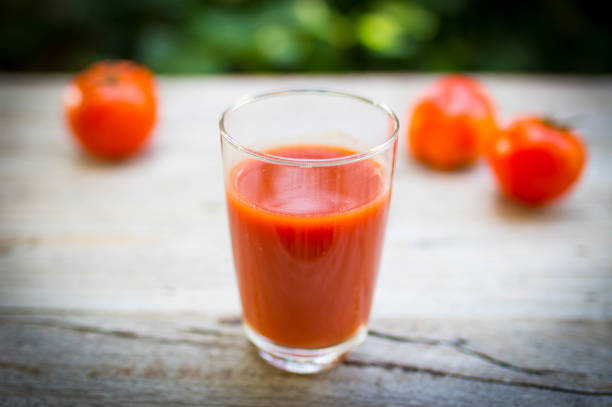 istock Tomato juice in clear glass on wooden table 665919190