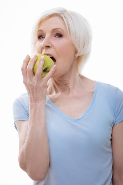 istock Portrait of elderly woman while biting green apple 665941246