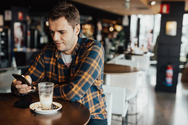istock Young adult in plaid shirt using phone 665949664