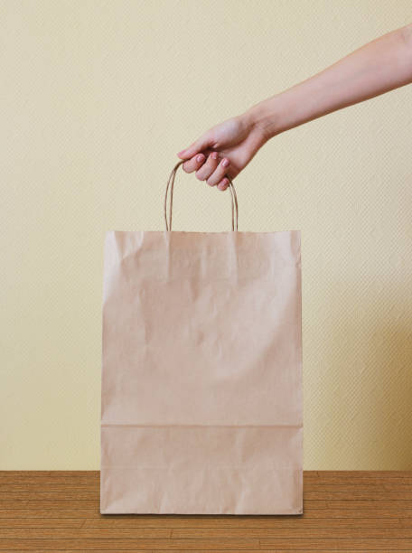 istock Hand holding a paper bag on wooden floor. 665950340