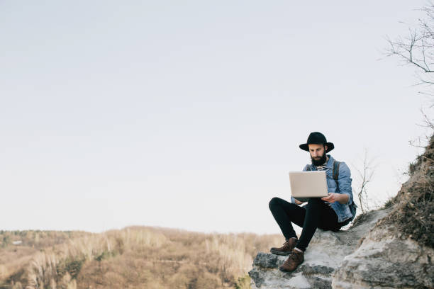istock handsome bearded man freelancer working on a laptop outdoors in mountains. Freelance concept 665951004