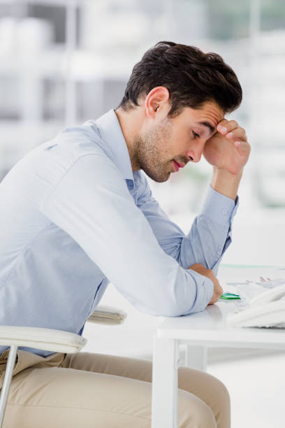 istock Frustrated businessman sitting on desk with hand on head 665958298