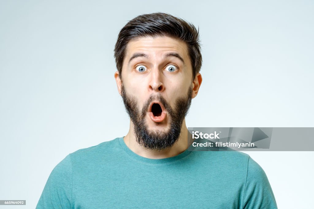 Man with shocked, amazed expression isolated on gray background Surprise Stock Photo