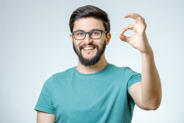 istock Everything is OK! Happy young man gesturing OK sign and smiling against gray background 665964116
