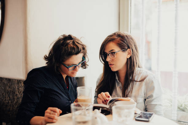 istock Two young woman are checking out the book in a cafe 665964632
