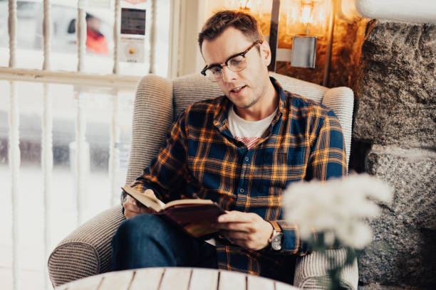 istock Man in plaid shirt is reading a book 665991210