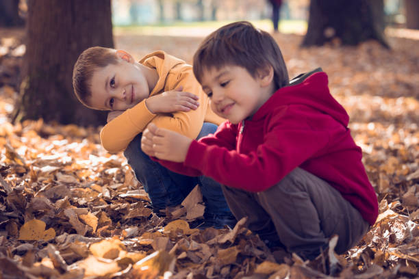 istock Two friends playing with autumn leaves in park 665991718