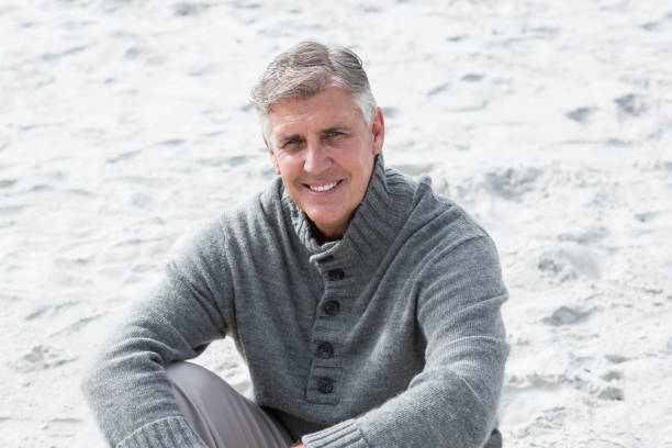 istock Smiling man sitting down in the sand 665997624
