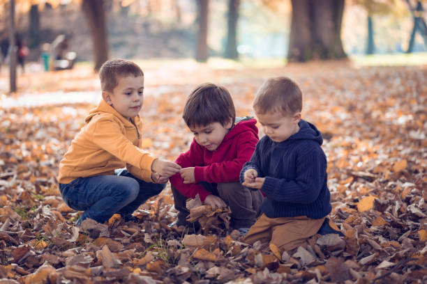 istock Three friends playing with autumn leaves in park 666003222