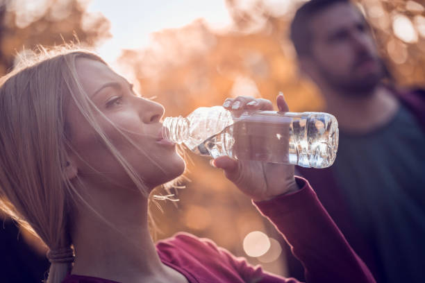 istock Man and women resting and drinking water after jogging in park 666021084