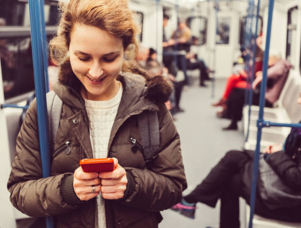istock Smiling woman using phone in the subway train 666023546