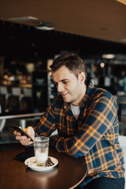 istock Handsome adult sitting in a cafe and using phone 666024732