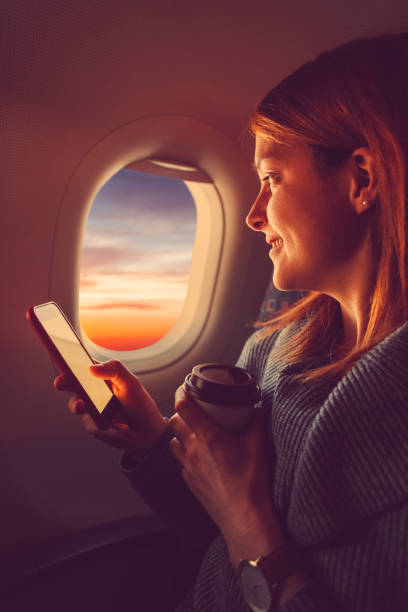 jeune femme en avion texting et de boire du café - airplane smart phone travel mobile phone photos et images de collection