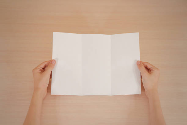 istock Hands holding blank white brochure booklet in the hand. Leaflet presentation. Pamphlet hand man. Show offset paper. Sheet template. Book in hands. Booklet folding design. Fold paper sheet display read 666036318