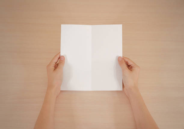 istock Hands holding blank white brochure booklet in the hand. Leaflet presentation. Pamphlet hand man. Show offset paper. Sheet template. Book in hands. Booklet folding design. Fold paper sheet display read 666036342