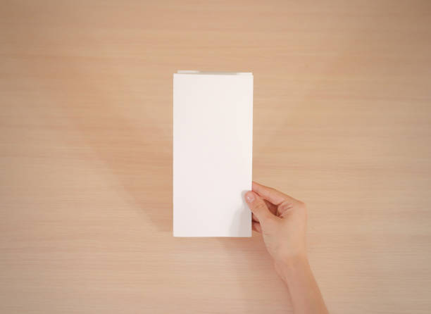 istock Hands holding blank white brochure booklet in the hand. Leaflet presentation. Pamphlet hand man. Show offset paper. Sheet template. Book in hands. Booklet folding design. Fold paper sheet display read 666036344