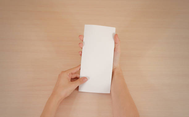 istock Hands holding blank white brochure booklet in the hand. Leaflet presentation. Pamphlet hand man. Show offset paper. Sheet template. Book in hands. Booklet folding design. Fold paper sheet display read 666036352