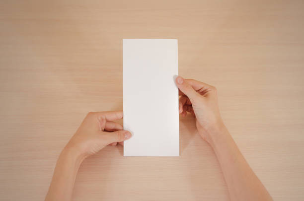istock Hands holding blank white brochure booklet in the hand. Leaflet presentation. Pamphlet hand man. Show offset paper. Sheet template. Book in hands. Booklet folding design. Fold paper sheet display read 666036354