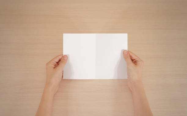 istock Hands holding blank white brochure booklet in the hand. Leaflet presentation. Pamphlet hand man. Show offset paper. Sheet template. Book in hands. Booklet folding design. Fold paper sheet display read 666036358