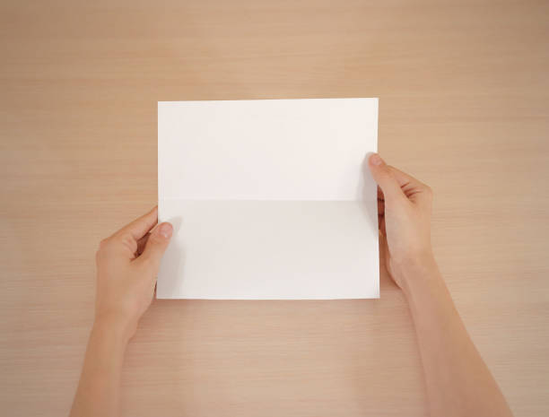 istock Hands holding blank white brochure booklet in the hand. Leaflet presentation. Pamphlet hand man. Show offset paper. Sheet template. Book in hands. Booklet folding design. Fold paper sheet display read 666036364