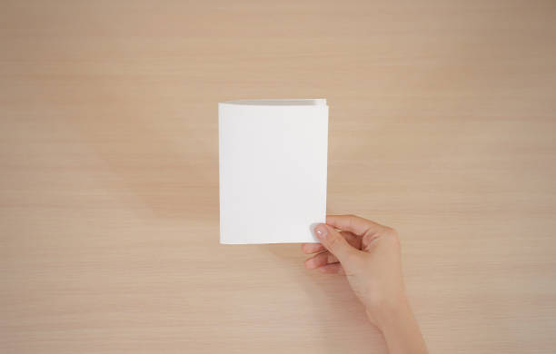 istock Hands holding blank white brochure booklet in the hand. Leaflet presentation. Pamphlet hand man. Show offset paper. Sheet template. Book in hands. Booklet folding design. Fold paper sheet display read 666036406