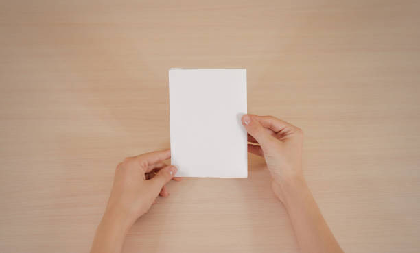 istock Hands holding blank white brochure booklet in the hand. Leaflet presentation. Pamphlet hand man. Show offset paper. Sheet template. Book in hands. Booklet folding design. Fold paper sheet display read 666036416