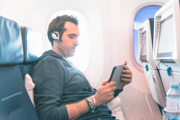 istock Man sitting on a plane watching something on his tablet 666037120
